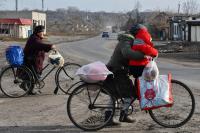 pessoas com bicicletas atravessam estrada de terra