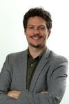 Homem de terno e braços cruzados sorrindo 