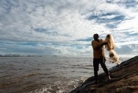 Imagem mostra pescador negro se preparando para lança a rede de pesca