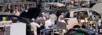 Foto mostra trabalhadores em uma fábrica de carros
