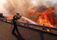 Bombeiro combate incêndio na Ronald Reagan Freeway, também conhecida como Highway 118, em Simi Valley, Califórnia (foto: Ringo H.W. Chiu / AP)
