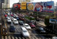 Pedestres se aproximam com cuidado de um cruzamento com carros em alta velocidade em Bancoc, na Tailândia