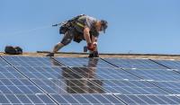 Trabalhador instala painel solar em telhado nos Estados Unidos