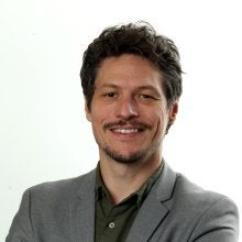 Homem de terno e braços cruzados sorrindo 