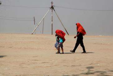 pessoas caminhando no deserto com a cabeça coberta por panos
