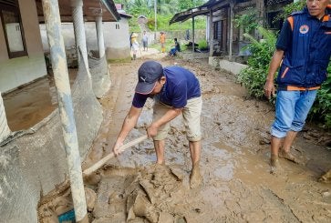 pessoa limpando lama em bairro da Indonésia