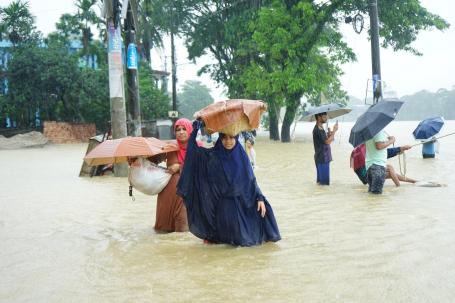 PEssoas cobrem a cabeça com sacos em meio a enchente em Bangladesh
