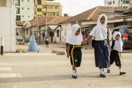 Três estudantes atravessam a rua em Dar es Salaam, na Tanzânia. 