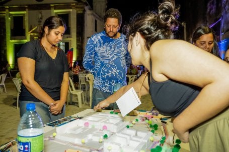 pessoas conversam em torno de maquete