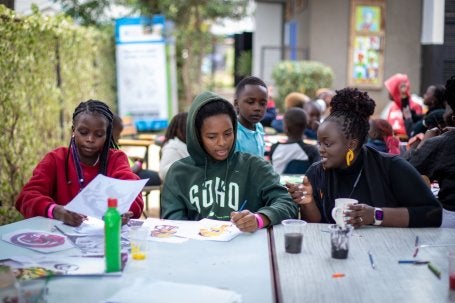 Marianne Wamuyu (à direita), diretora de programas e eventos do Book Bunk Trust, trabalha com estudantes durante uma sessão do Art Bunk na Biblioteca Eastlands. 