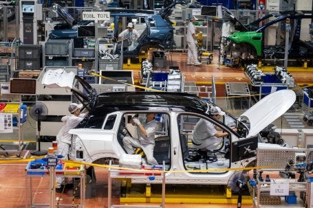 Trabalhadores montam um veículo elétrico: na China, metade de todos os carros vendidos em 2025 eram elétricos, o que ajuda a reduzir a importação de petróleo e gás natural. (Foto: Ringo Chiu/Shutterstock)