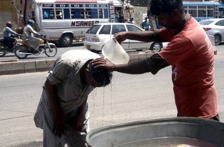 Água é despejada sobre a cabeça de um homem durante para refresca-lo durante uma onda de calor em Karachi, no Paquistão: temperaturas escaldantes são cada vez mais comuns na cidade. 