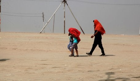 pessoas caminhando no deserto com a cabeça coberta por panos