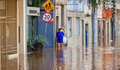 pessoa caminha em meio a enchente em porto alegre