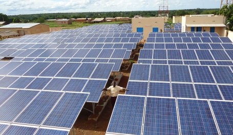 homem negro em país africano em meio a dezenas de paineis solares
