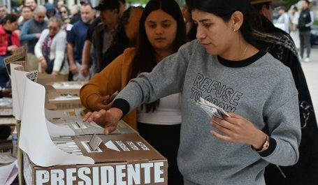 mulher deposita voto na urna no México