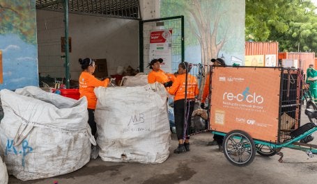 mulheres em meio a sacolas de lixo reciclável