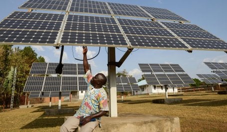 homem em uganda próximo a painel de energia solar
