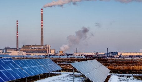 Paineis solares e usina de carvão ao fundo
