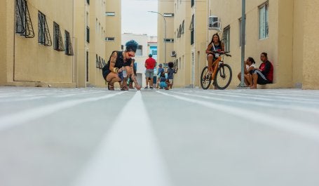 pessoas pintam o chão entre prédios