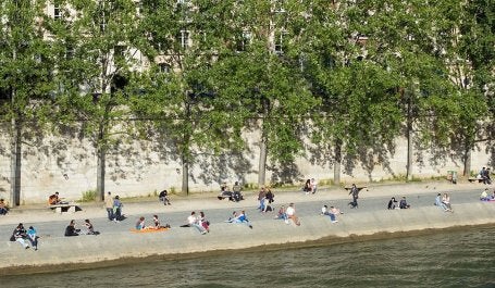 Pessoas descansam às margens do rio Sena, em Paris. A França está entre os países que têm avançado na elaboração de estratégias de longo prazo que alinham metas climáticas e de desenvolvimento para proteger as comunidades e fortalecer a resiliência. (Foto: mrstam/iStock) 