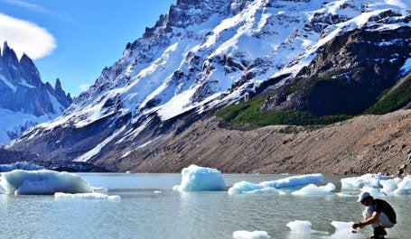 imagem de homem examinando lago congelado próximo a cordilheira dos andes