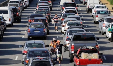 vendedores ambulantes em meio a carros em congestionamento