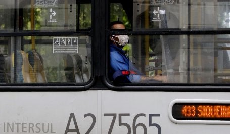 homem dentro de ônibus público com janela aberta e máscara
