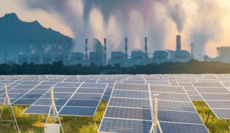 poluição em segundo plano com painéis solares de energia limpa em primeiro plano