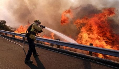Bombeiro combate incêndio na Ronald Reagan Freeway, também conhecida como Highway 118, em Simi Valley, Califórnia (foto: Ringo H.W. Chiu / AP)