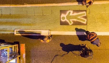 imagem de homens pintando faixa de pedestres no chão de rua