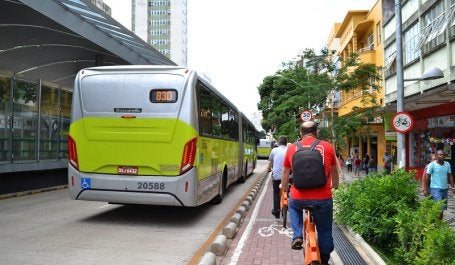 imagem mostra homem em ciclovia e ônibus na pista ao lado