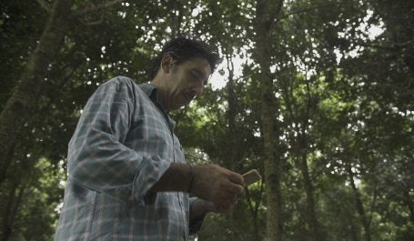 Homem na floresta olha para celular