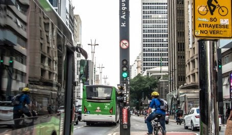 homem em bicicleta em ciclovia de são paulo aguarda semáforo em cruzamento da rua augusta