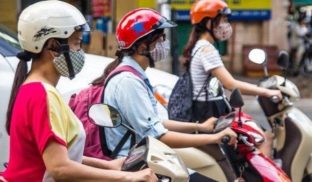 mulheres em motos usando máscaras de proteção em Hanoi, no Vietnã