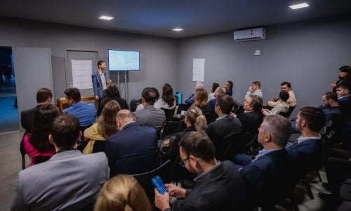 pessoas em sala de reuniões assistem homem falando