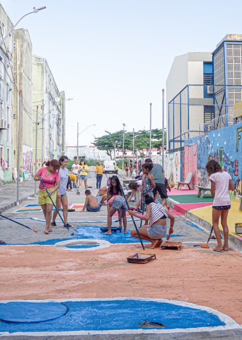 Adultos e crianças pintam rua em residencial em região vulnerável